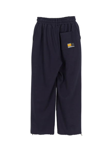 Men's Curved Fit Sweatpants (Dark Blue) IL502 Dark blue flat-lay back view showing Universal 91 woven patch on back pocket elastic waist and ankle zipper pullers