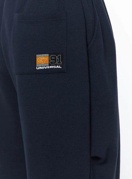 Men's Curved Fit Sweatpants (Dark Blue) IL502 Dark blue close-up detail of back pocket with woven Universal 91 patch badge on fleece fabric