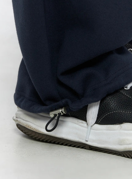 Men's Curved Fit Sweatpants (Dark Blue) IL502 Dark blue close-up detail of hem showing drawstring cinch zipper puller at ankle cuff over sneaker