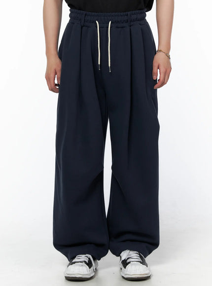 Men's Curved Fit Sweatpants (Dark Blue) IL502 Dark blue front close-up on model showing cream drawstring elastic waistband and pleated wide-leg cut