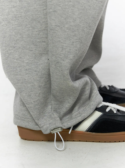 Men's Curved Fit Sweatpants (Gray) IL502 gray close-up detail of hem with adjustable drawcord stopper and wide stacked leg opening on sneaker