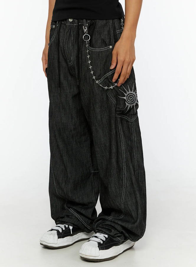 LEWKIN Men's Dale Embroidered Baggy Jeans IL509 black close-up side view on female model hand in pocket showing sun embroidery and silver chain detail