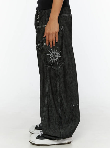 Men's Dale Embroidered Baggy Jeans IL509 black side view on female model hand in pocket showing sun embroidery and silver cross chain on denim