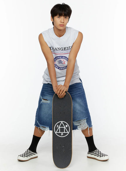 Men's Distressed Jorts IL509 Blue full-length front view on male model leaning on skateboard wearing white sleeveless Los Angeles graphic tee