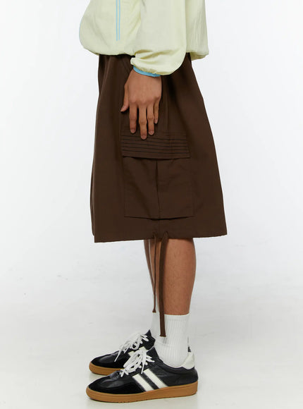 Men's Drawstring Cargo Shorts IL515 Brown side shot on model showing large cargo pocket with pintuck ribbed flap and side drawstring tie at hem