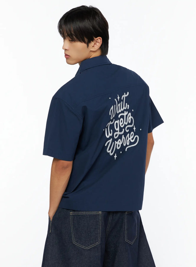 Men's Embroidered Button-Up Shirt IL528 Navy back shot on model showing cursive Wait it gets Worse embroidery with sparkle details paired with denim shorts
