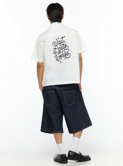 Men's Embroidered Button-Up Shirt IL528 White back shot on model showing cursive Wait it gets Worse embroidery styled with wide-leg denim shorts and loafers