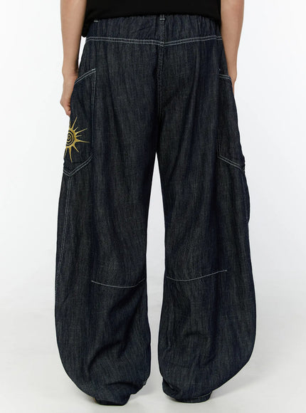 Men's Embroidered Wide Leg Jeans IU529 Dark blue back view cropped waist-down on model, showing elastic waistband, back pockets, gold sun embroidery, and wide balloon legs