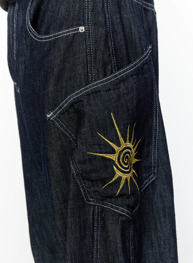 Men's Embroidered Wide Leg Jeans IU529 Dark blue close-up detail of side cargo pocket with gold sun spiral embroidery and white contrast stitching on dark denim