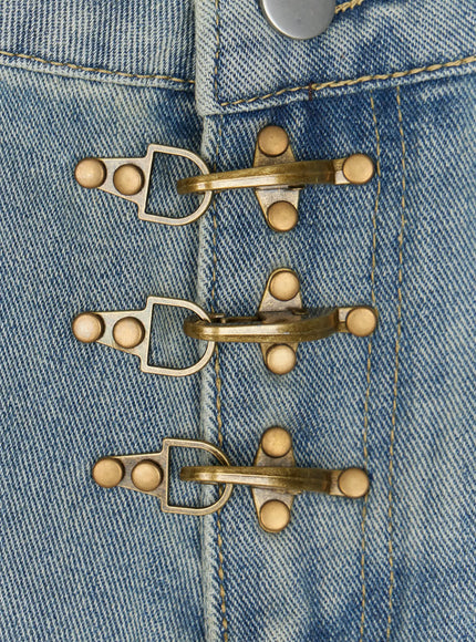 Men's Fireman Clasp Baggy Jeans IL507 Light blue close-up detail of three antiqued brass fireman clasp hooks with rivet studs on light blue denim fabric