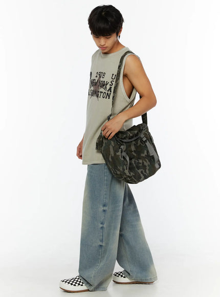 Men's Fireman Clasp Baggy Jeans IL507 Light blue lifestyle side-angle view on male model carrying camo bag, styled with graphic sleeveless tee and checkered sneakers