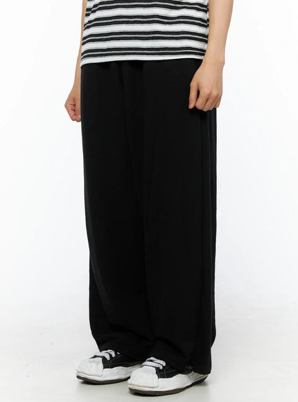 Men's Flame Wide Sweatpants (Black) IL514 three-quarter front view on model showing wide-leg cut, relaxed drape, and cotton fleece texture paired with striped tee
