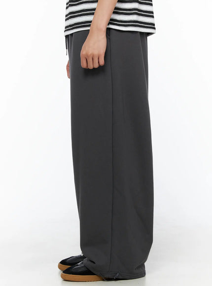 Men's Flame Wide Sweatpants (Dark Gray) IL514 Dark gray side view on model showing smooth wide-leg silhouette and ankle zip adjuster detail with sneakers