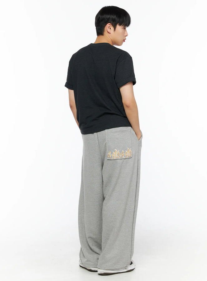 LEWKIN Men's Flame Wide Sweatpants (Gray) IL514 Gray back shot on male model standing with hands in pockets showing flame embroidery on rear pocket