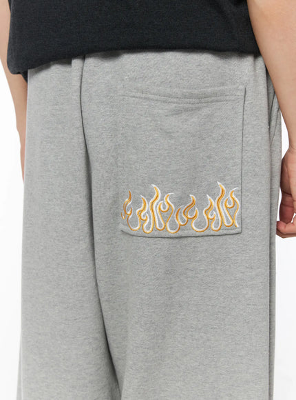 Men's Flame Wide Sweatpants (Gray) IL514 Gray close-up detail of golden flame embroidery on back patch pocket with heathered fleece texture