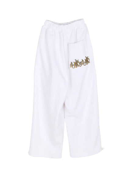 Men's Flame Wide Sweatpants (White) IL514 White flat-lay back view showing gold and black flame embroidery on rear pocket, wide-leg cut and ankle drawstring on white background