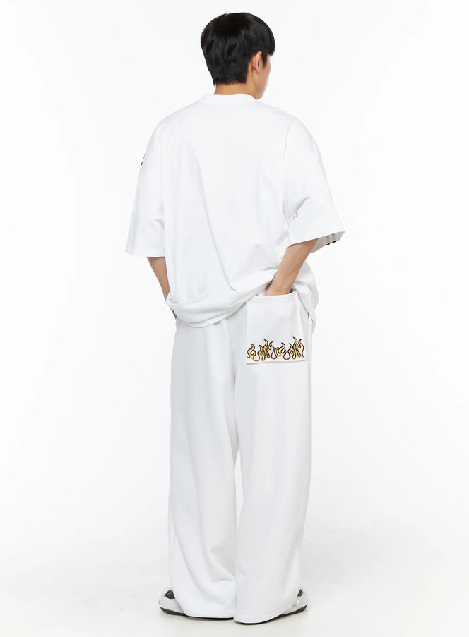 Men's Flame Wide Sweatpants (White) IL514 White back view on male model styled with oversized white graphic tee, flame embroidered back pocket visible, wide-leg silhouette