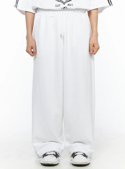 Men's Flame Wide Sweatpants (White) IL514 White front close-up on male model showing elastic drawstring waistband detail and wide-leg drape, cropped at hip to ankle