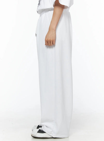 Men's Flame Wide Sweatpants (White) IL514 White side view on male model showing side pocket and wide-leg fleece fabric, styled with graphic tee and chunky sneakers