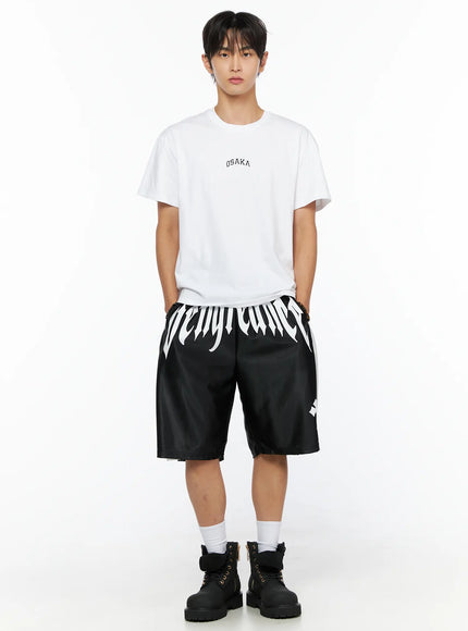 Men's Gothic Print Athletic Shorts IL515 Black full-body front shot on male model styled with white OSAKA graphic tee and black boots, gothic logo at waistband