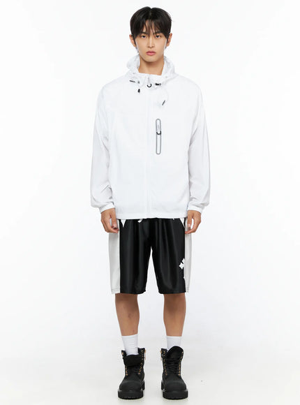 Men's Gothic Print Athletic Shorts IL515 Black full-body front shot on male model wearing white zip-up windbreaker jacket, cross print visible on shorts hem