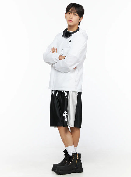 Men's Gothic Print Athletic Shorts IL515 Black full-body side-angle styling shot on male model with arms crossed, white windbreaker jacket and black boots