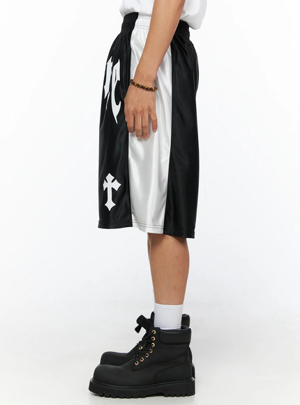 Men's Gothic Print Athletic Shorts IL515 Black side view close-up on model showing white contrast side panel, cross graphic, and satin mesh texture with elastic waist