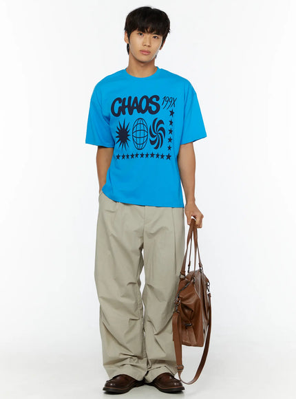 Men's Graphic Chaos T-Shirt IL509 Blue full-body front shot on male model holding brown tote bag at side styled with beige wide-leg trousers and loafers