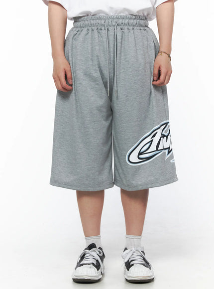 LEWKIN Men's Graphic Logo Shorts (Gray) IL502 Gray M/L front view on model wearing white tee, elasticized drawstring waist, bold graphic logo print on hem