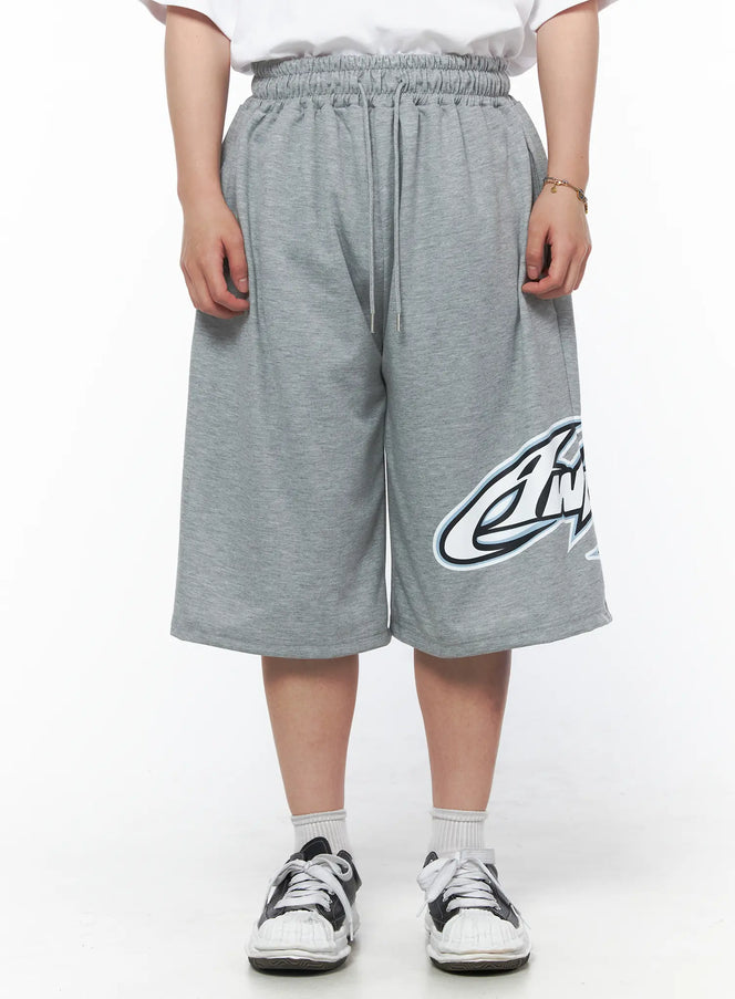 LEWKIN Men's Graphic Logo Shorts (Gray) IL502 Gray M/L front view on model wearing white tee, elasticized drawstring waist, bold graphic logo print on hem