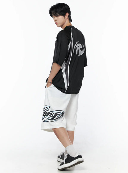 Men's Graphic Logo Shorts (White) IL502 White full-body back view on male model walking, back logo graphic visible, black mesh top styling, sneakers