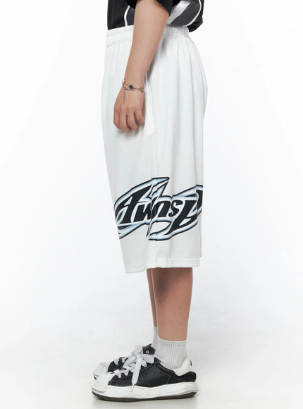 Men's Graphic Logo Shorts (White) IL502 White back view on model, back patch pocket detail, elastic waistband, secondary oval logo graphic on back left leg
