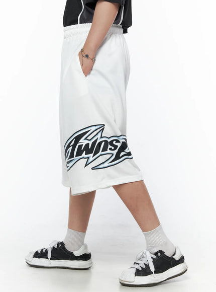 LEWKIN Men's Graphic Logo Shorts (White) IL502 White side view on model walking, hand in pocket, large Twins graphic print on hem, elastic waistband