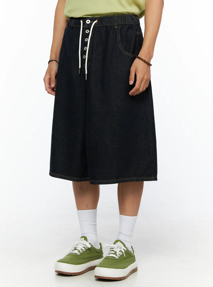 Men's Graphic Loose-Fit Shorts IL515 Dark blue close-up lower-body view on female model showing wide-leg silhouette, elastic waistband and drawstring lace-up detail