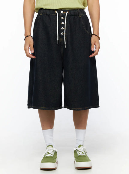 LEWKIN Men's Graphic Loose-Fit Shorts IL515 Dark blue front view on female model wearing green top and green sneakers, wide-leg denim with drawstring lace-up closure