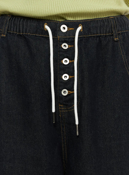 Men's Graphic Loose-Fit Shorts IL515 Dark blue close-up detail of drawstring lace-up front closure with silver eyelets and white cord, contrast amber topstitching on dark denim