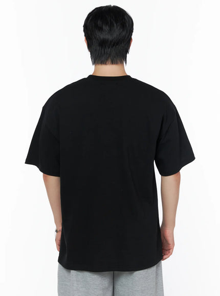 Men's Graphic Oversized T-Shirt IL502 Black back shot on male model, plain clean back panel, dropped shoulders, oversized cotton silhouette, paired with gray shorts