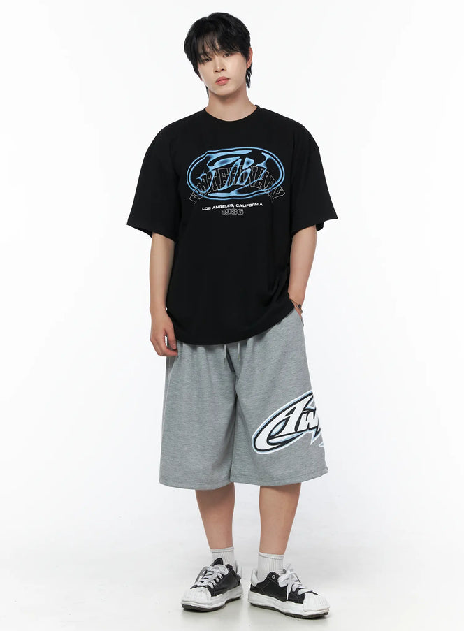 Men's Graphic Oversized T-Shirt IL502 Black front shot on male model full body, blue oval graphic print, Los Angeles California 1986 text, styled with gray logo shorts and sneakers