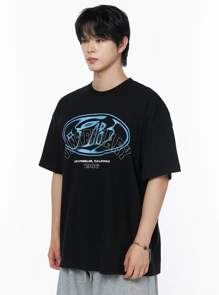 Men's Graphic Oversized T-Shirt IL502 Black close-up front shot on male model, blue oval Los Angeles California 1986 chest graphic detail, three-quarter crop showing print clearly