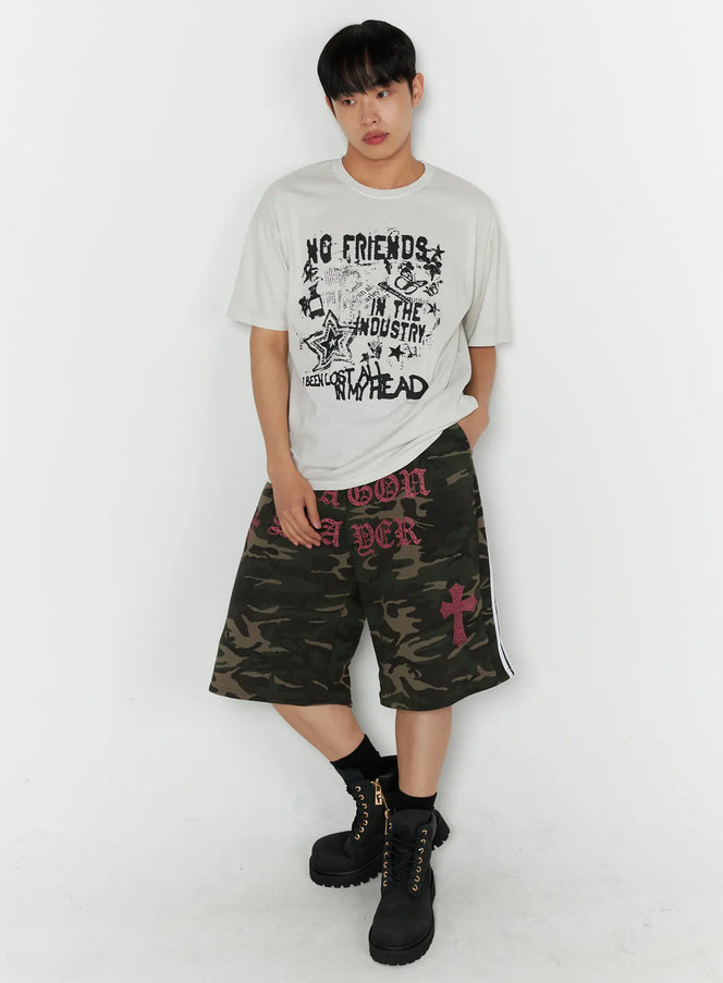 Men's Graphic Pigment Dyed Tee IL514 Light beige full-body front shot on male model standing with hands in pockets styled with camo shorts and boots