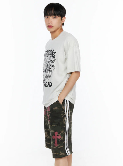 Men's Graphic Pigment Dyed Tee IL514 Light beige side shot on male model with hand in pocket showing graphic print depth oversized silhouette and sleeve length