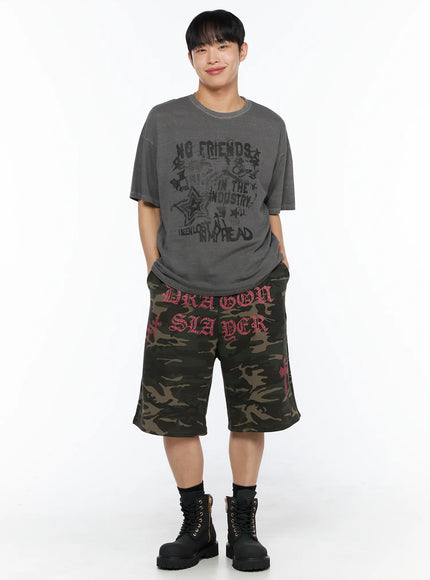 Men's Graphic Pigment Dyed Tee IL514 Charcoal grey full-body front shot on male model smiling hands in pockets relaxed oversized fit styled with camo shorts