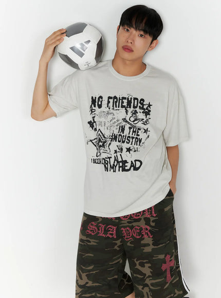LEWKIN Men's Graphic Pigment Dyed Tee IL514 Light beige front shot on male model holding soccer ball wearing camo shorts oversized fit