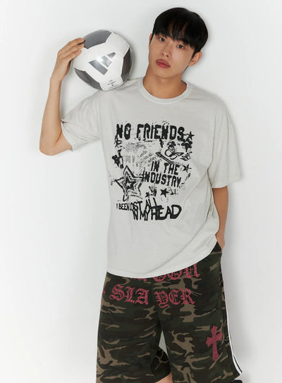 LEWKIN Men's Graphic Pigment Dyed Tee IL514 Light beige front shot on male model holding soccer ball wearing camo shorts oversized fit