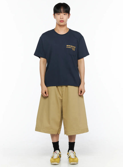 Men's Graphic Pocket Tee IL514 Navy front full-body view on male model styled with khaki wide shorts, black socks and yellow sneakers, relaxed cotton silhouette