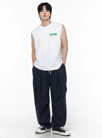 Men's Graphic Print Sleeveless Tee IL502 White front full-body shot on male model hands in pockets relaxed stance with navy drawstring trousers