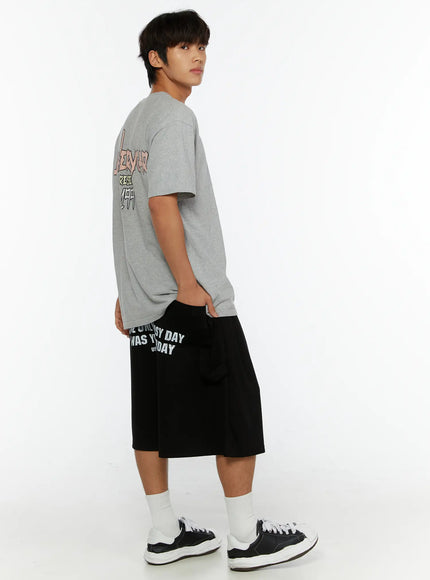Men's Graphic Print Sweat Shorts IL515 Black full-body back side view on male model showing US Navy Seals graphic print and wide-leg silhouette