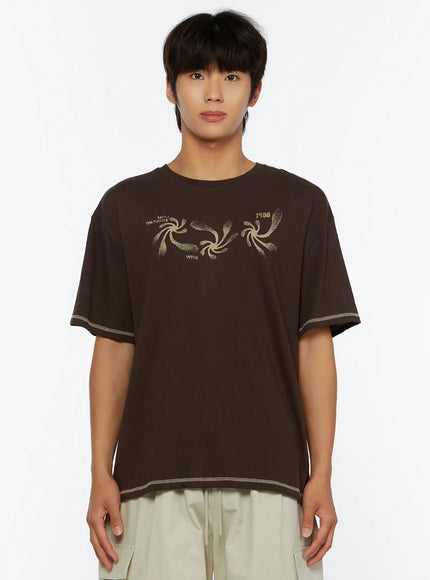 Men's Graphic Print T-Shirt IL513 Dark brown close-up front view on male model showing swirl graphic print contrast stitch hem and sleeve details