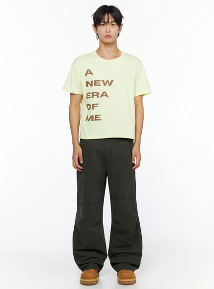 Men's Graphic Semi-Crop T-Shirt IL528 light yellow front shot on male model arms relaxed showing brown A NEW ERA OF ME graphic print and cropped cotton silhouette