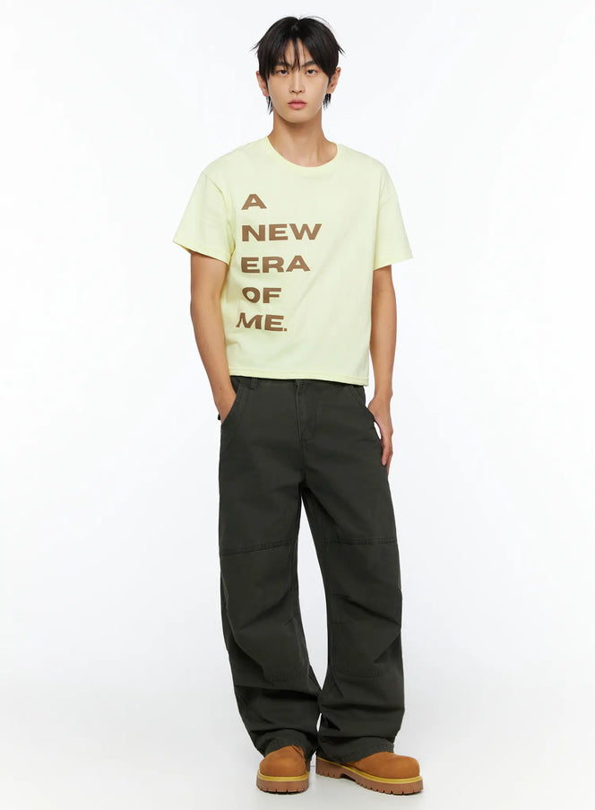 LEWKIN Men's Graphic Semi-Crop T-Shirt IL528 light yellow front shot on male model standing straight styled with dark olive wide-leg pants and tan boots